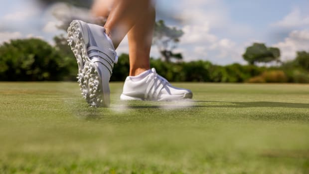 Side view of white adidas golf shoes.